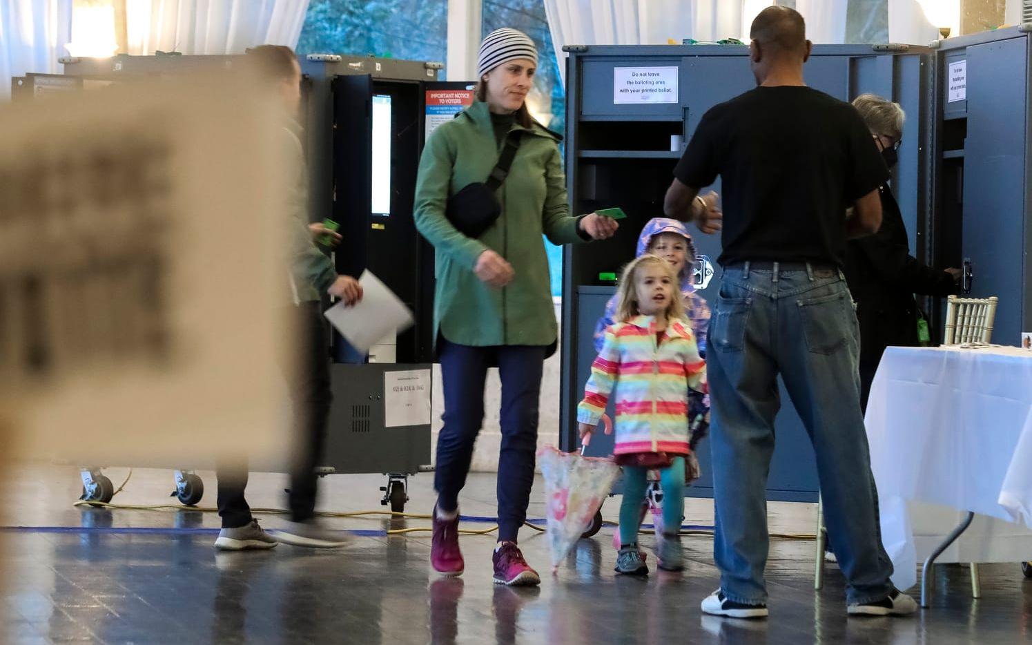 Emily Taylor röstar med sina döttrar Grace och Margaret, och ger valsedeln till valarbetaren Errol Webbon i en vallokal i Atlanta.