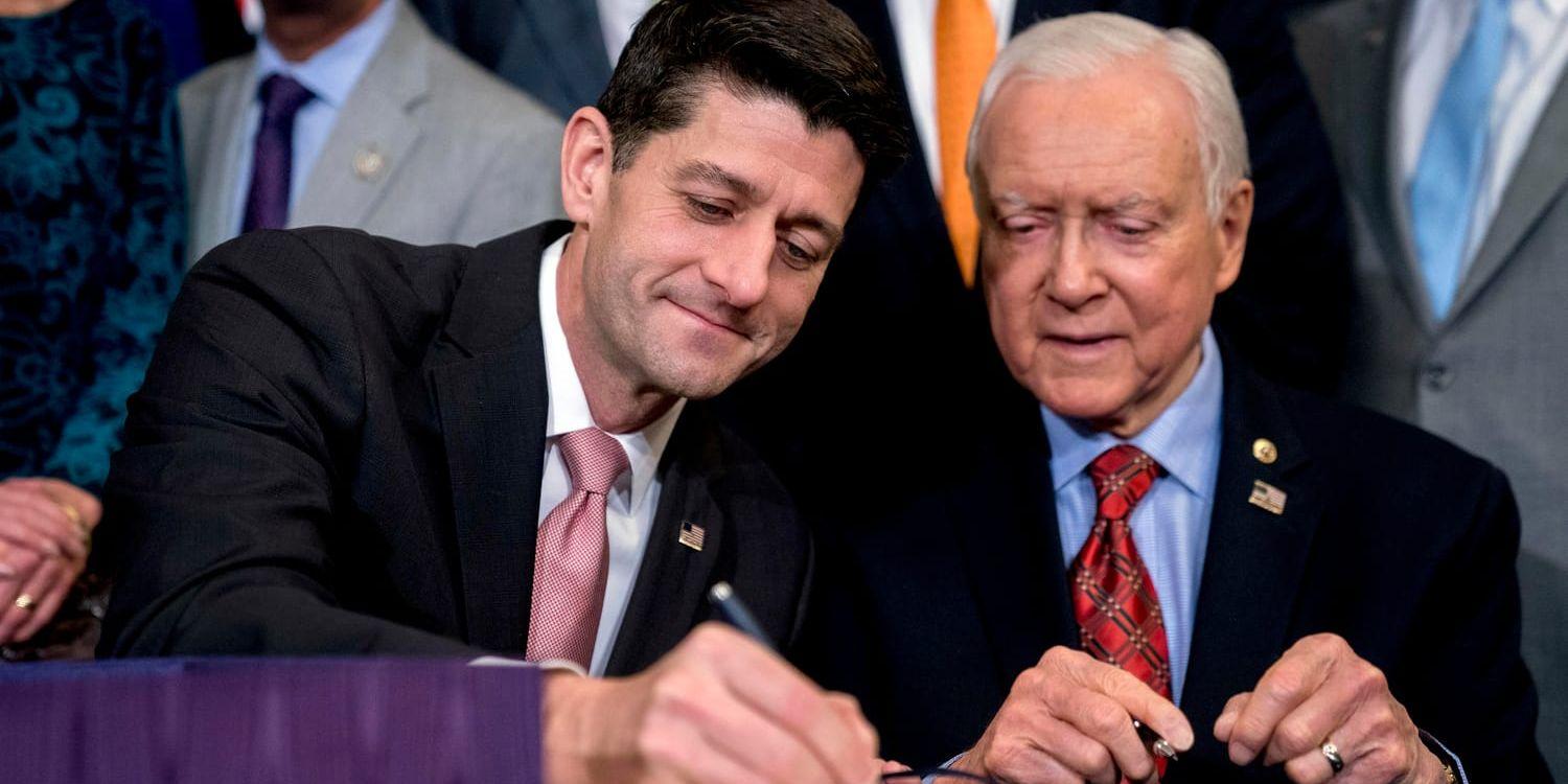 Representanthusets talman Paul Ryan (till vänster) undertecknar höjningen av skuldtaket tillsammans med ordföranden för senatens finansutskott Orrin Hatch (till höger). Båda representerar högerpartiet Republikanerna.