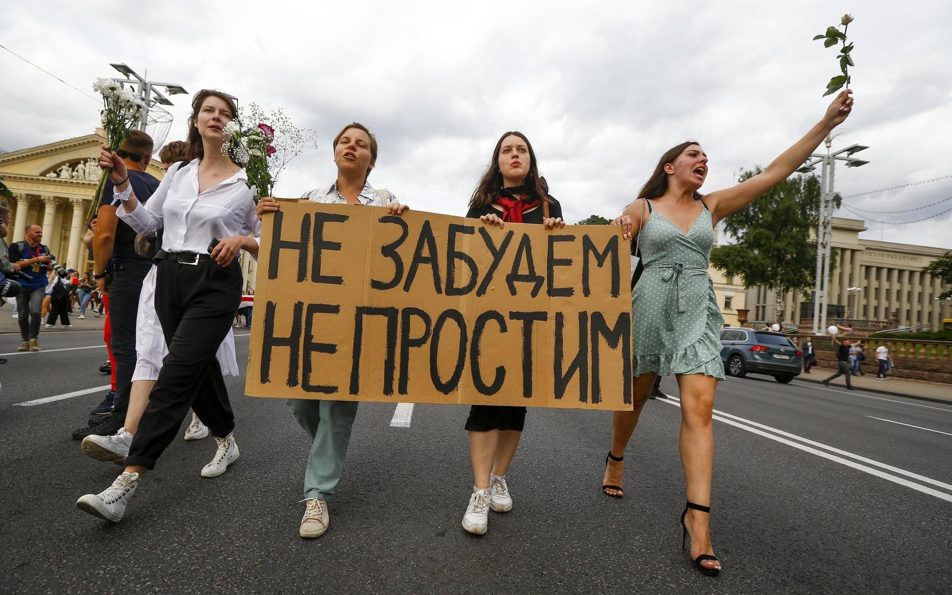 Kvinnor marscherar med banderoller där det står ”Vi kommer inte glömma, vi kommer inte förlåta” i centrala Minsk under fredagen. 