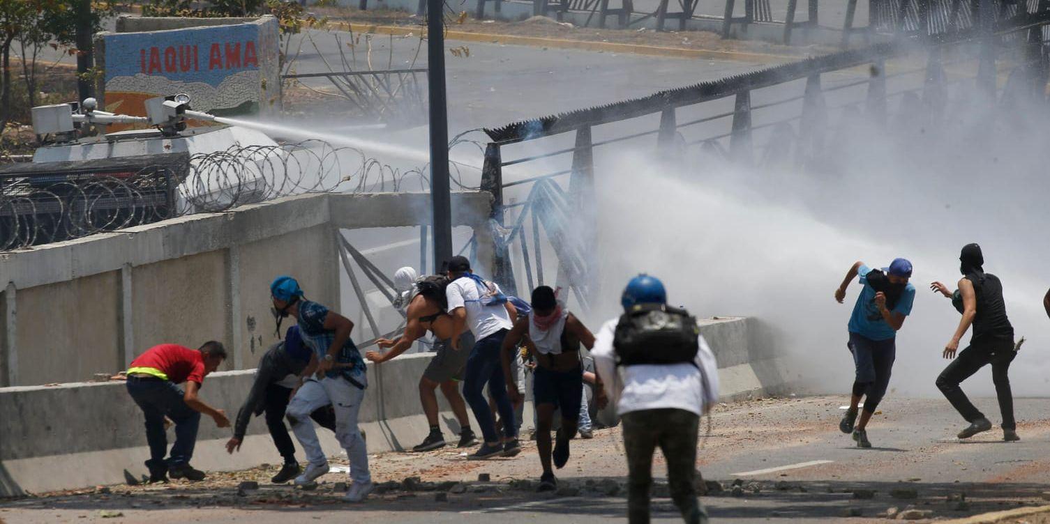 Demonstranter möts av vattenkanoner vid flygbasen La Carlota.