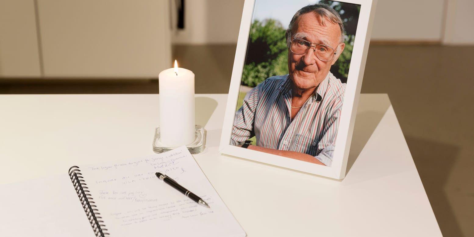 En kondoleansbok bredvid ett tänt ljus och ett fotografi på Ingvar Kamprad framställt på Ikea museet i Älmhult.
