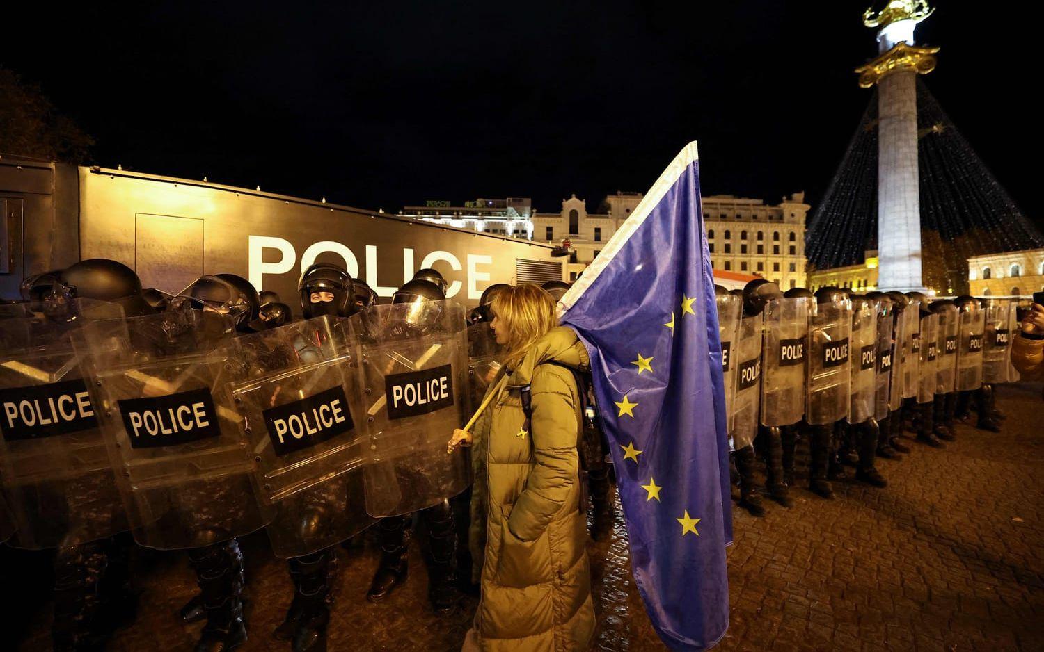 En kvinna med EU-flagga konfronterar kravallutrustad polis i Georgiens huvudstad Tbilisi på torsdagen.