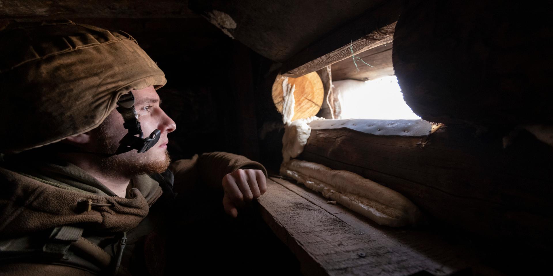 En ukrainsk soldat spanar genom värnet vid fronten mot de ryskstödda separatisterna i Donetsk-regionen i östra Ukraina. Inför en ny befarad rysk invasion och krissamtal mellan Ryssland, USA och Nato råder en spänt väntan efter åtta års fruktlöst krig med över 13 000 döda.