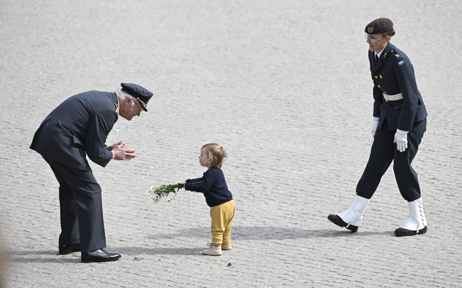 Ett litet barn ger blommor till kung Carl Gustaf.