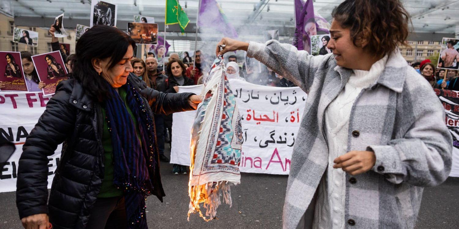Iranska kvinnor bränner sina huvuddukar under en protest mot Masha Aminis död. Amini, en 22-årig kvinna som dog i Iran medan hon satt i polisens förvar, greps av Irans moralpolis för att ha brutit mot dess strikt upprätthållna klädkod.