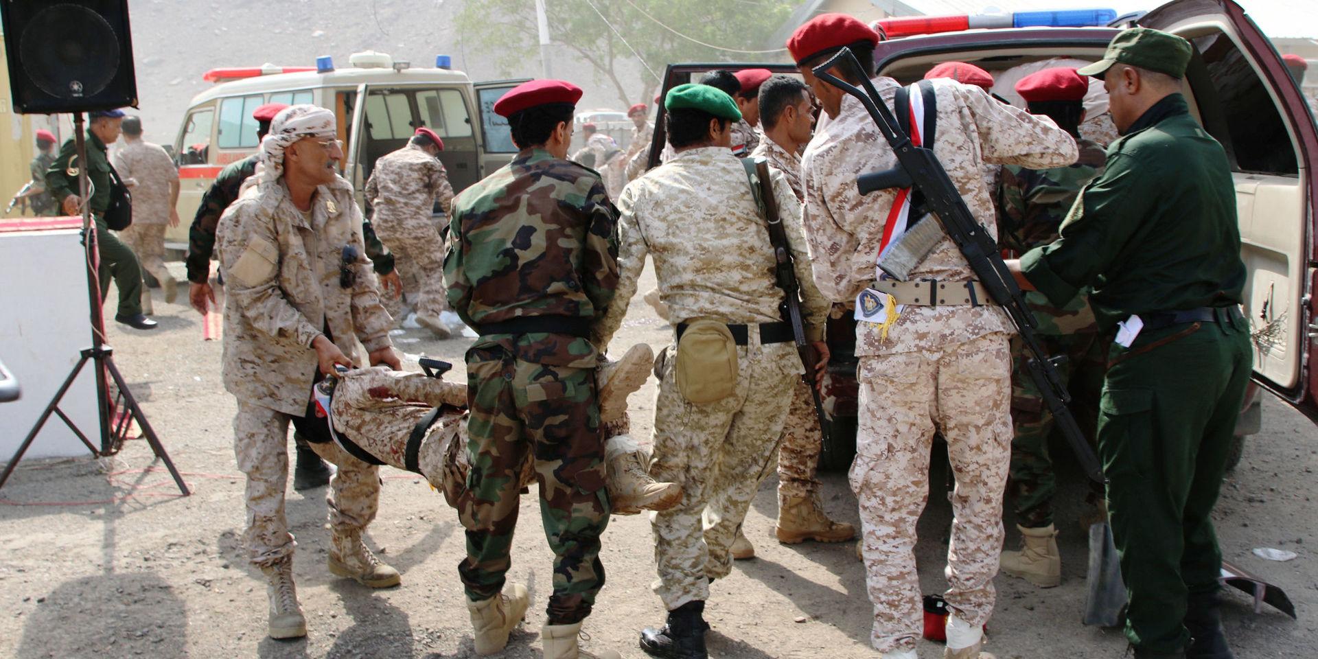 Soldater hjälper en skadad kollega efter attacken mot en militärparad i Aden, Jemen. 