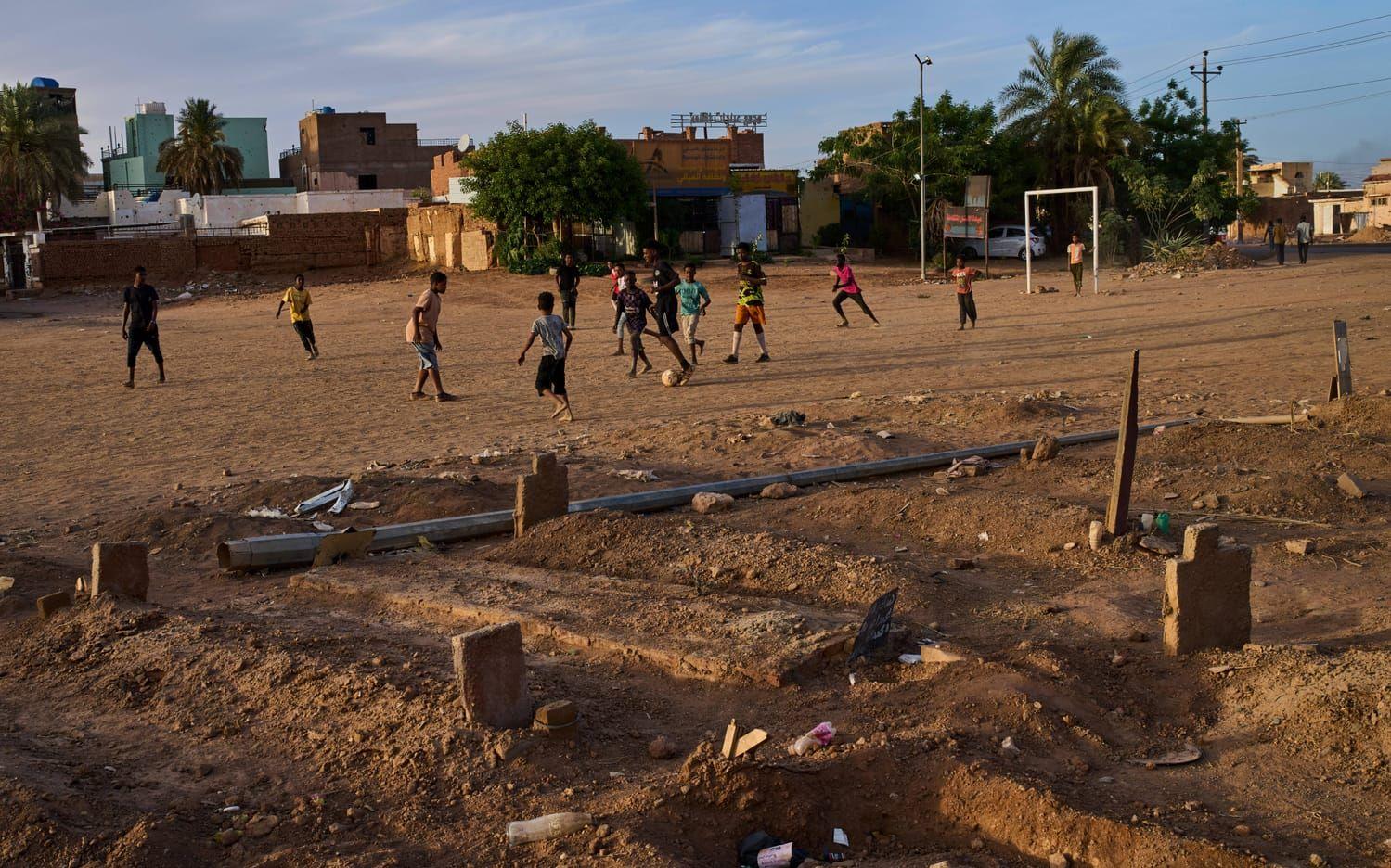 Unga sudaneser spelar fotboll nära en provisorisk gravplats i utkanten Omdurman, nära Sudans huvudstad Khartum. Bilden togs i slutet av april. 