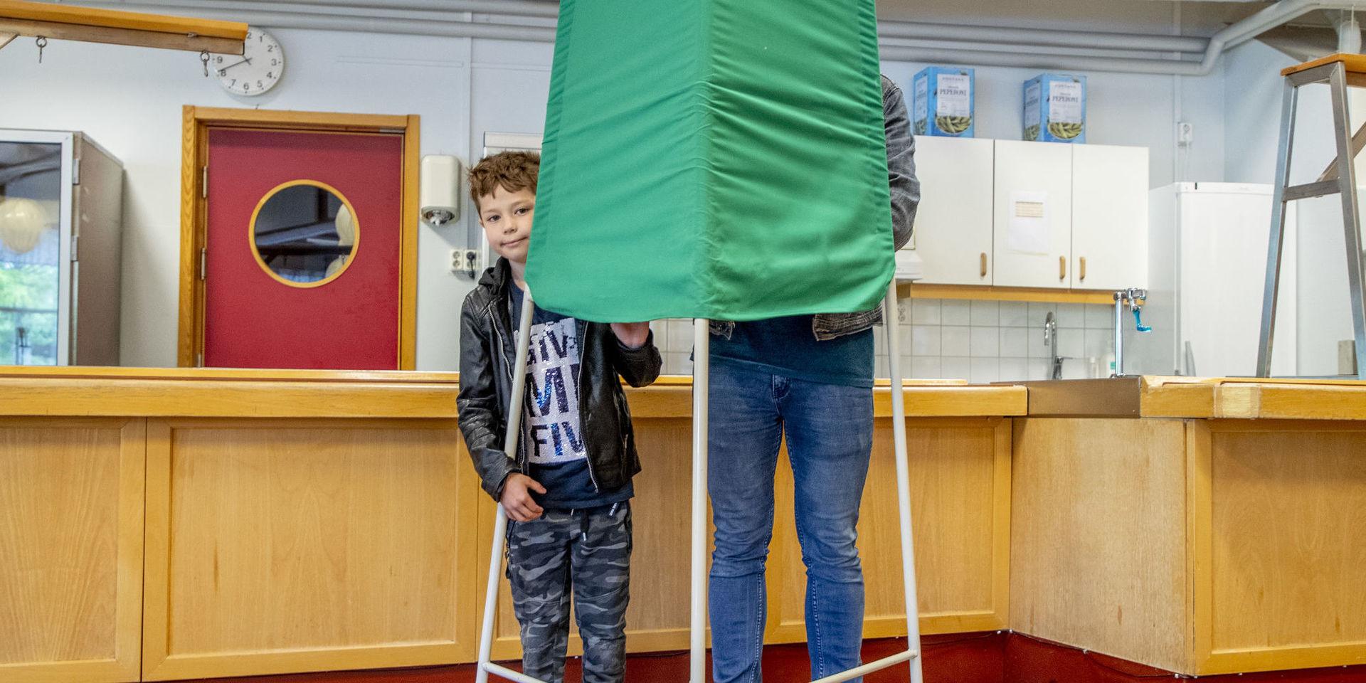 Vincent tittar fram bakom röstbåset medans pappa Martin Barkestedt röstar till EU-valet i matsalen på Lerums Gymnasium.
