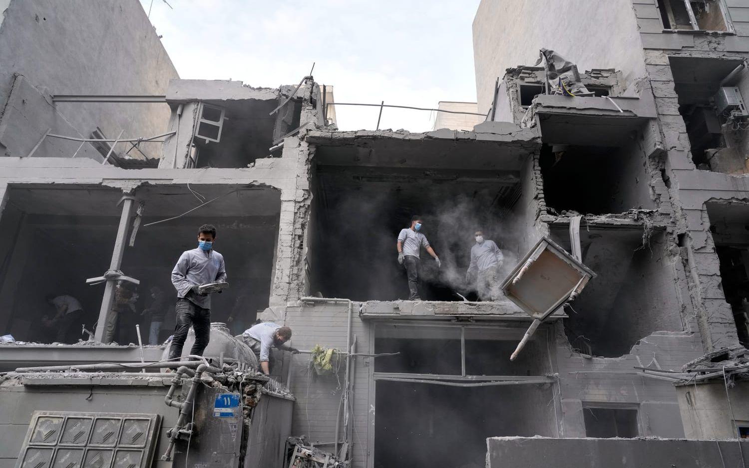 Frivilliga röjer efter att en byggnad träffats i en attack mot Irans huvudstad Teheran.