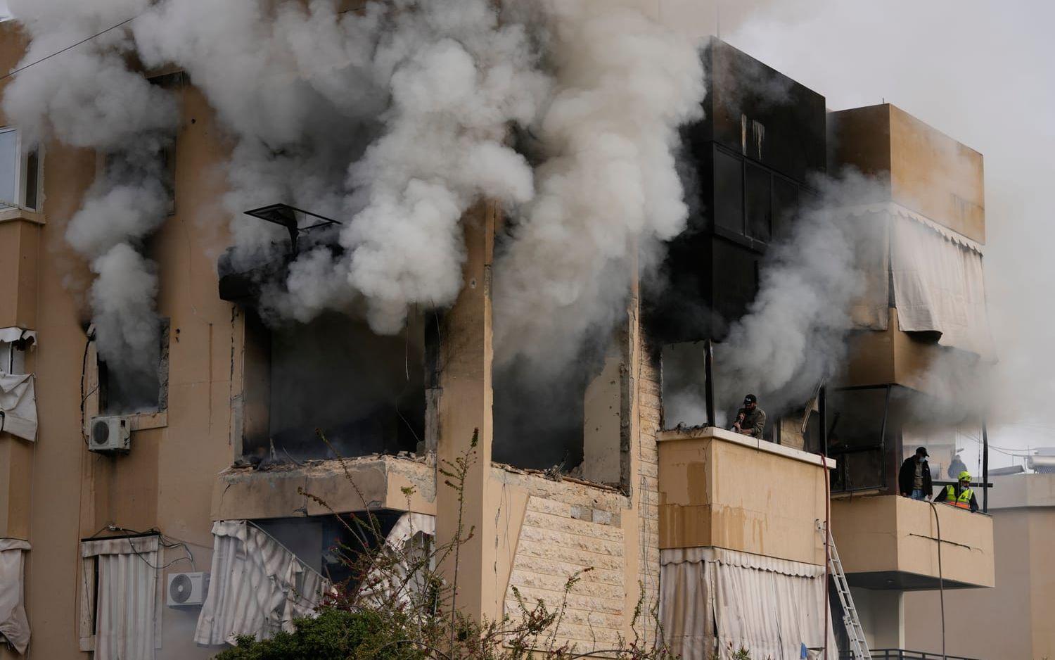 Räddningsarbetare inspekterar skadorna medan röken bolmar efter en israelisk attack mot ett bostadshus i den libanesiska hamnstaden Sidon.