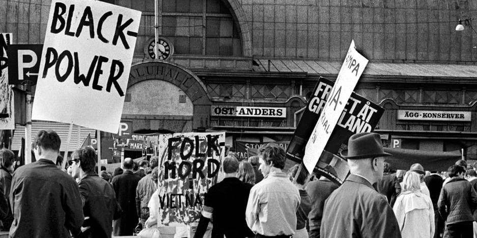 Svartvitt foto av förstamajdemonstration på Kungstorget i Göteborg, med plakat som ”Black power” och ”Folkmord i Vietnam”. 