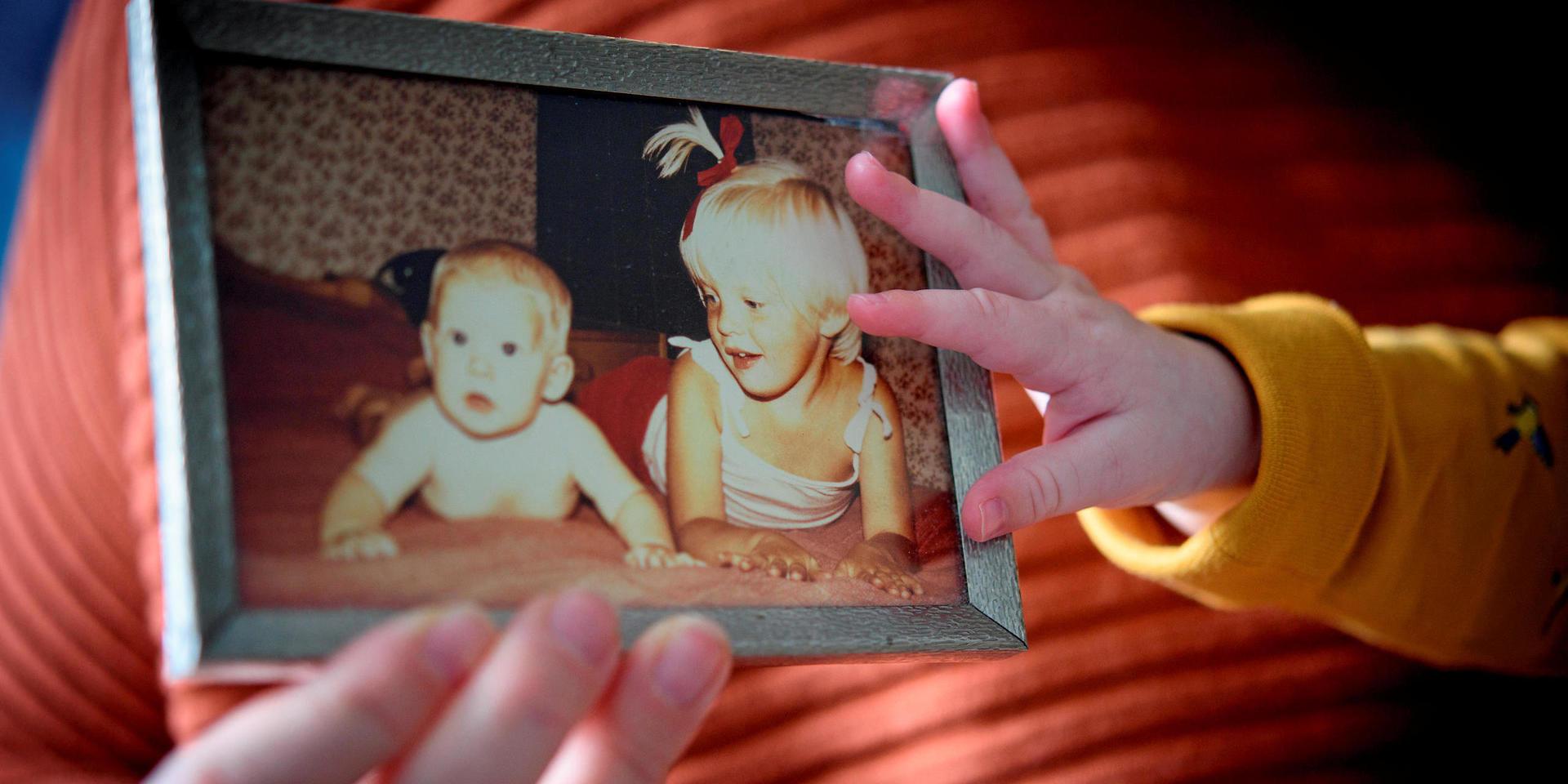 Helena visar upp en bild på sig själv och storasyster Johanna. Den lilla handen till höger tillhör Helenas son Otto. Han är fem månader, ungefär lika gammal som Helena (till vänster) är på fotografiet. 