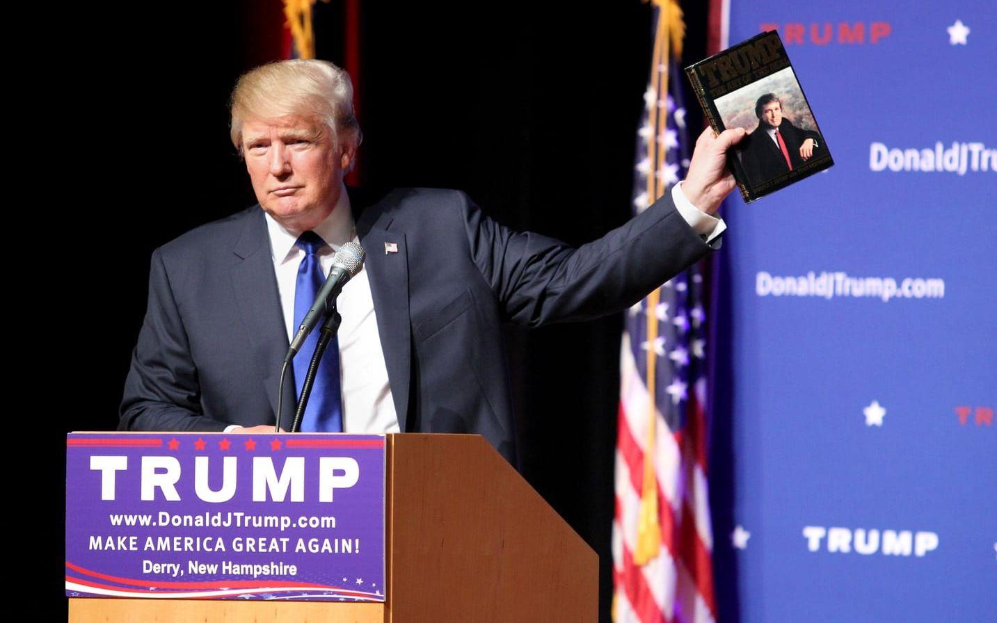 Valrörelsen 2015: Donald Trump håller upp sin bok 'The art of the deal' vid ett möte med väljare i New Hampshire.