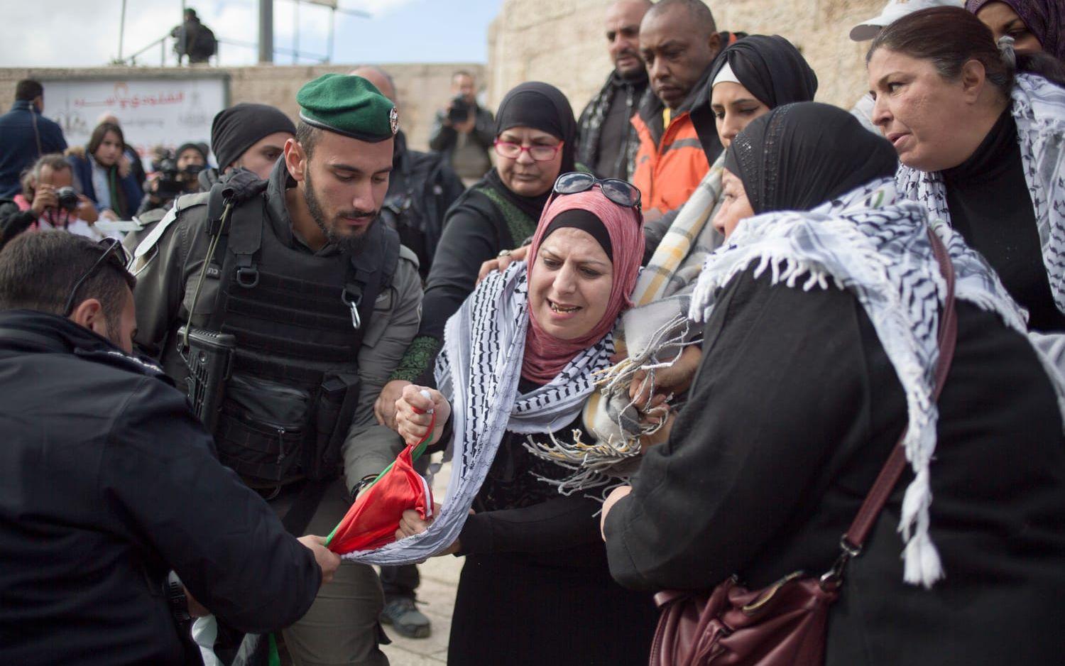Israeliska poliser försöker ta en palestinsk flagga från kvinnor som protesterar i Jerusalem. Bild: Ariel Schalit/TT.