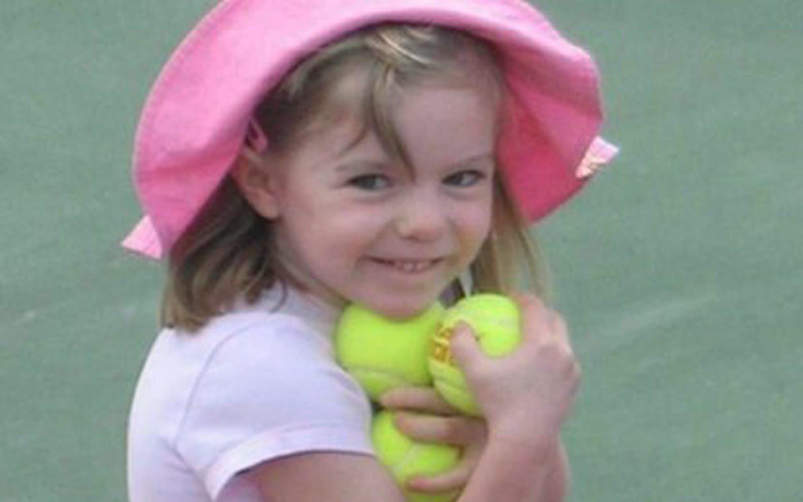Liten flicka med rosa hatt och gröna tennisbollar i famnen.