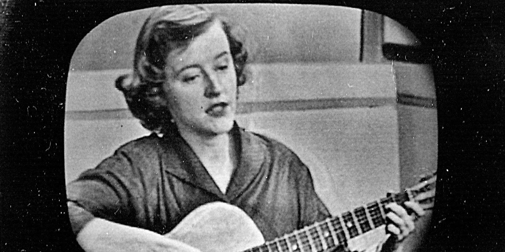 Connie Converse spelar gitarr under en tv-sändning i svartvitt.