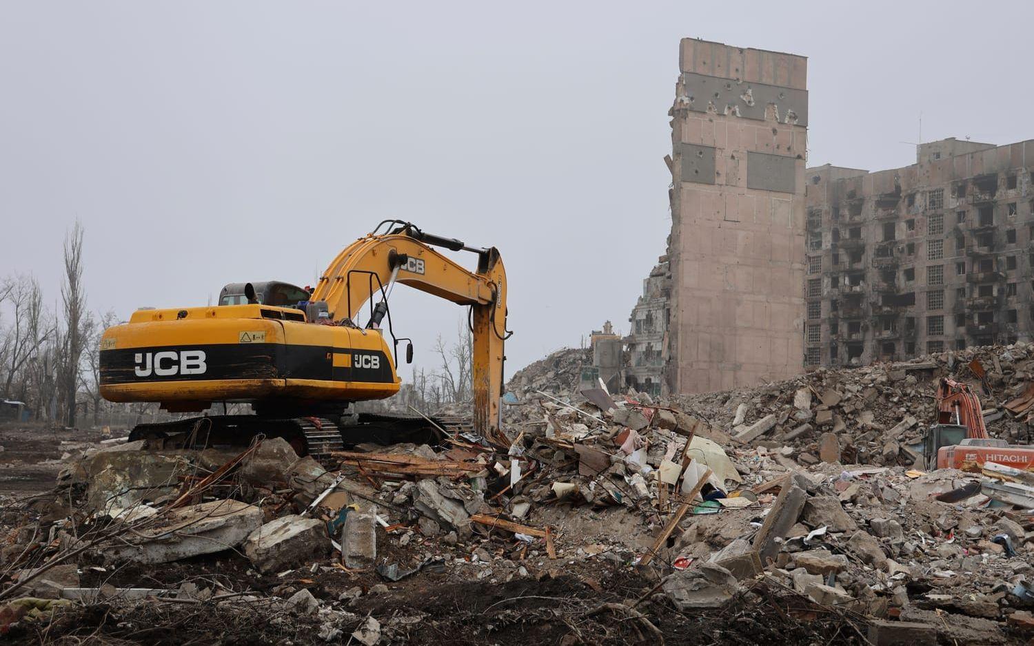 Grävmaskiner rensar undan bland rasmassor i Mariupol i december 2022. Arkivbild.