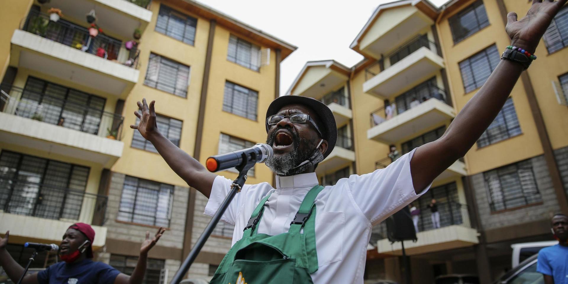 Paul Machira sjunger och predikar för boende i ett lägenhetsområde i den kenyanska huvudstaden Nairobi. Runt om honom sjunger och dansar barn på sina balkonger. 