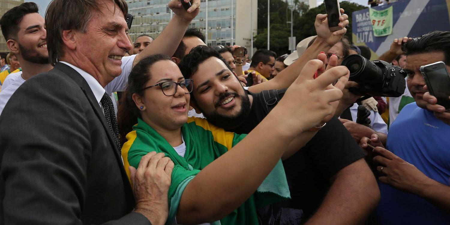 Ultrahögerkandidaten och kongressledamoten Jair Bolsonaro ställer upp på bild med anhängare vid en demonstration i Brasilia tidigare i april.