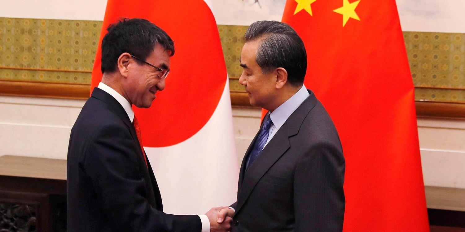 Taro Kono skakar hand med Wang Yi inför de två utrikesministrarnas möte i Peking.