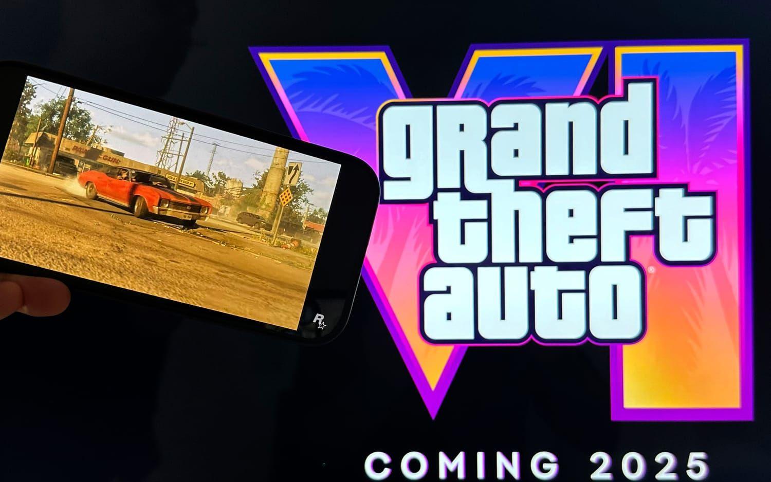 En mobil som håller upp en trailer för GTA 6 där en röd bil kör. I bakgrunden loggan för spelet i neonfärger.