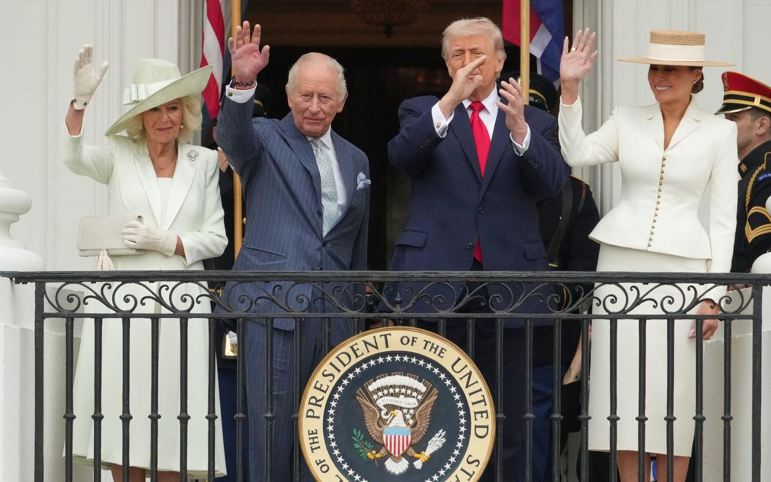Den brittiska drottningen Camilla, kung Charles och USA:s president Donald Trump och dennes hustru Melania Trump vinkar från en balkong i Vita huset. 