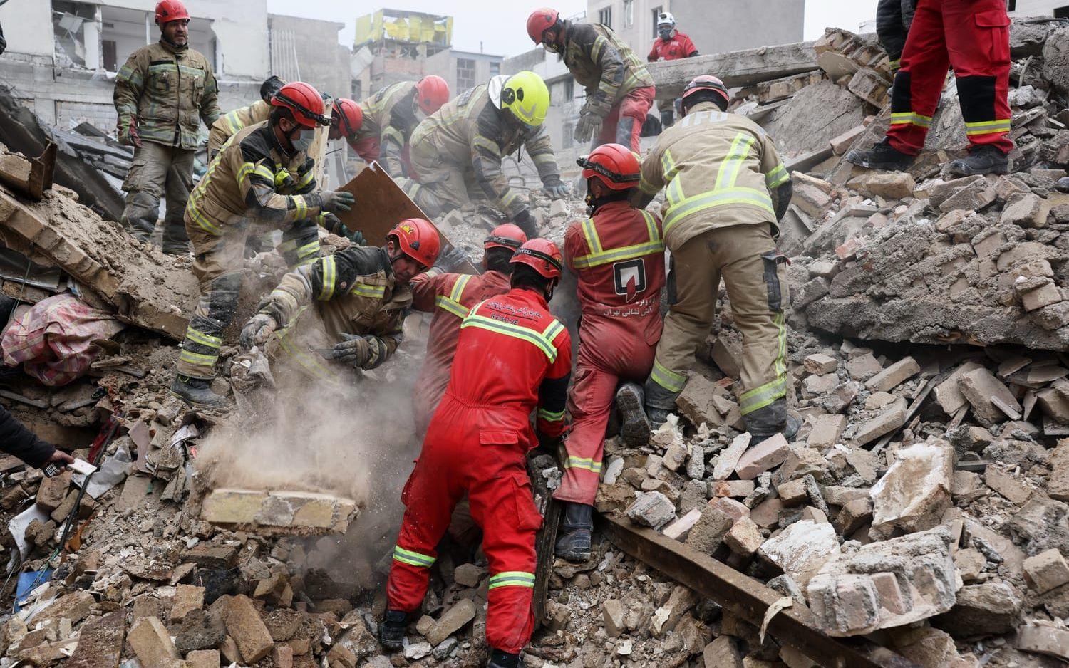 Räddningsarbetare letar efter överlevande i en förstörd byggnad i södra Teheran.