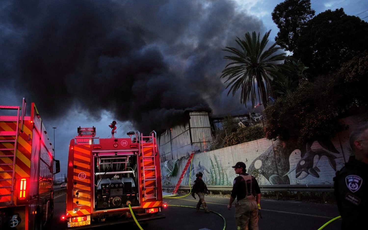 Brandmän kämpar mot lågorna i en byggnad efter att en iransk robot slagit ned i Holon strax söder om Tel Aviv.