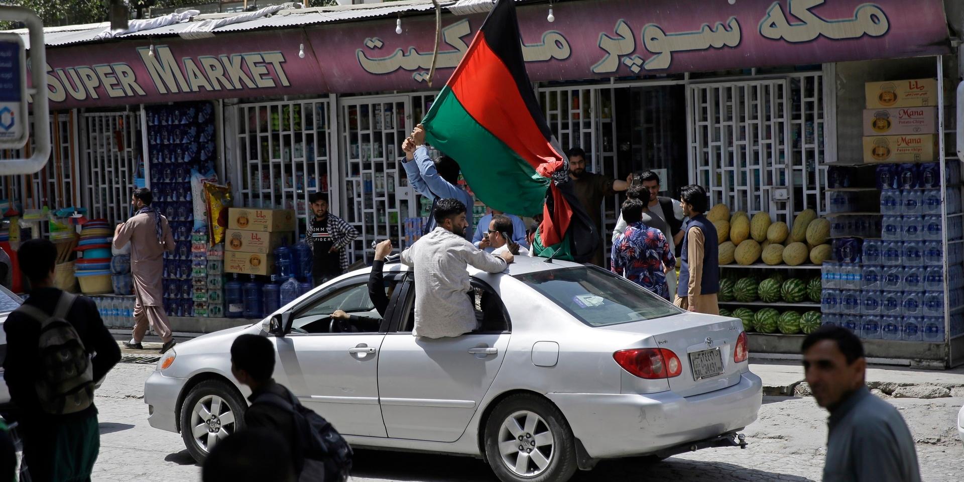 Afghaner viftar med den svarta, röda och gröna flaggan, som nu blivit en symbol för motstånd mot talibanerna. 