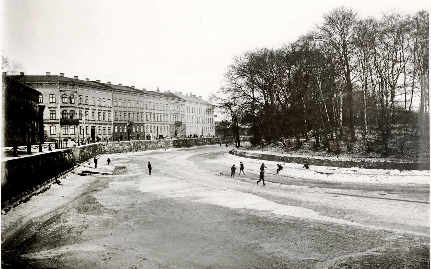 Barn som leker i Vallgraven en vinterdag. Stora Nygatan syns till vänster och Trädgårdsföreningen till höger. Bilden är tagen runt 1900.