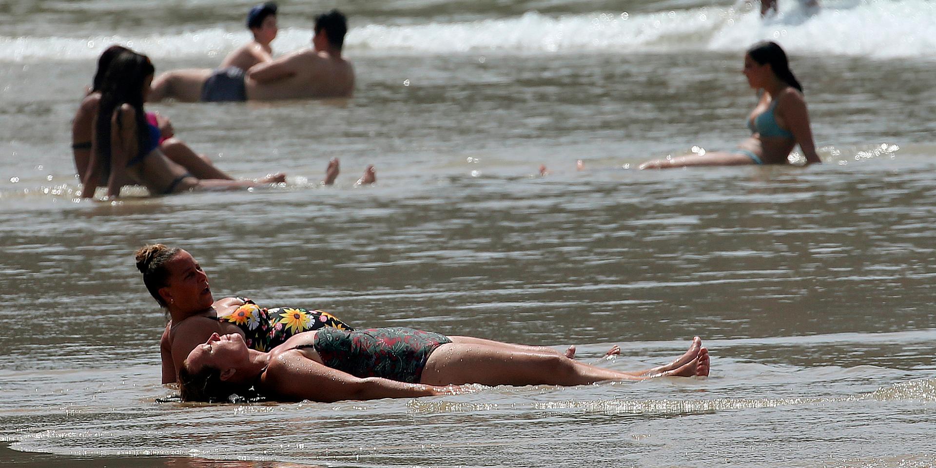 Människor svalkar sig i havet i Biarritz i sydvästra Frankrike efter att temperaturen under lördagen uppgått till 43 grader.