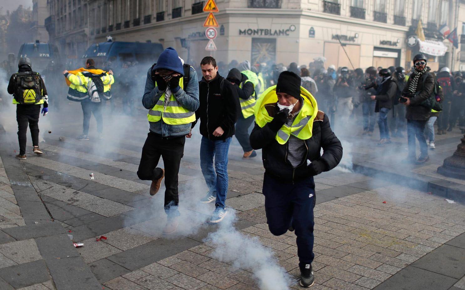 Demonstranter flyr efter att polis avfyrat tårgas.