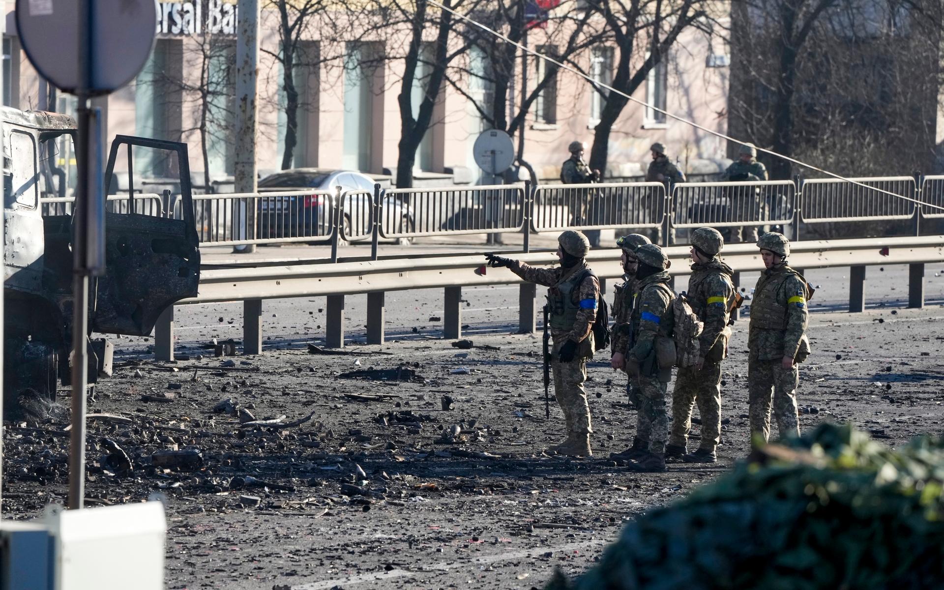 Ukrainska soldater vid ett utbränt militärfordon i Kiev.