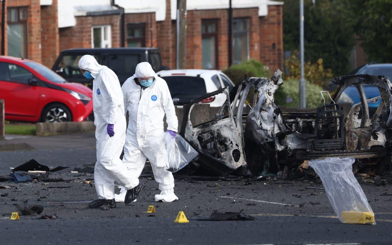 Utredare granskar platsen där en bomb exploderade utanför en polisstation i Belfast förra helgen.