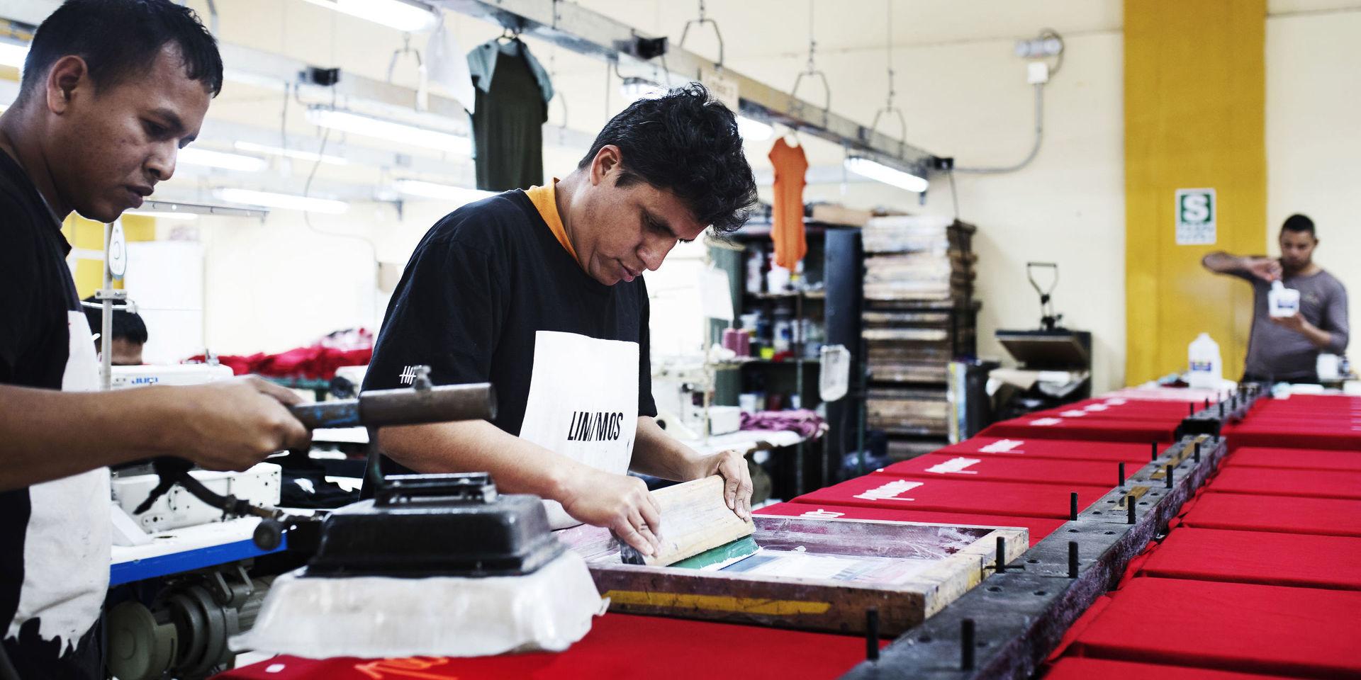 Med silkscreentryck märker Huaman de illröda tröjorna med texten ”peruano” (peruan). 