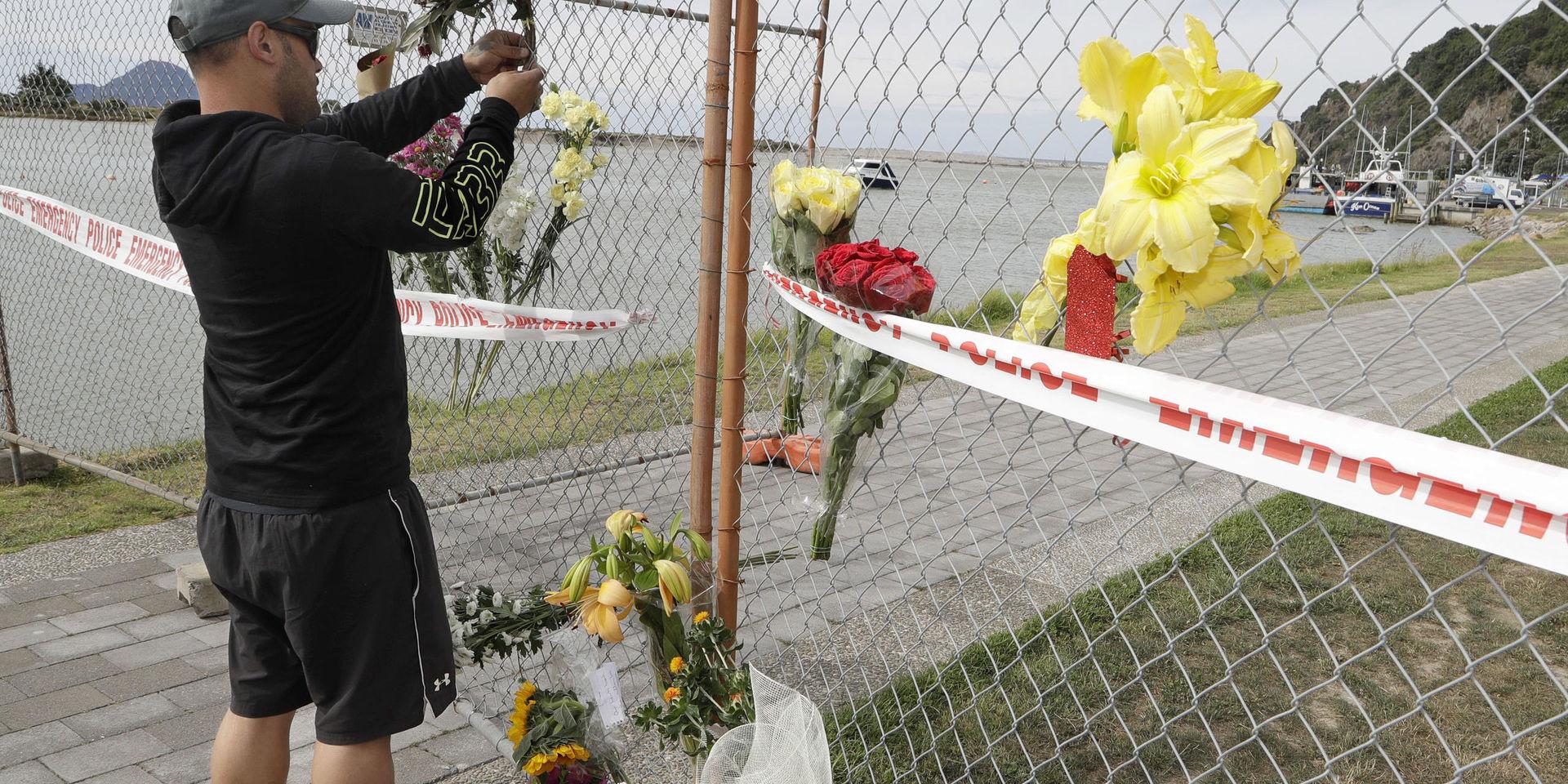 En man lämnar blommor till minne av de omkomna efter vulkanutbrottet på White Island.