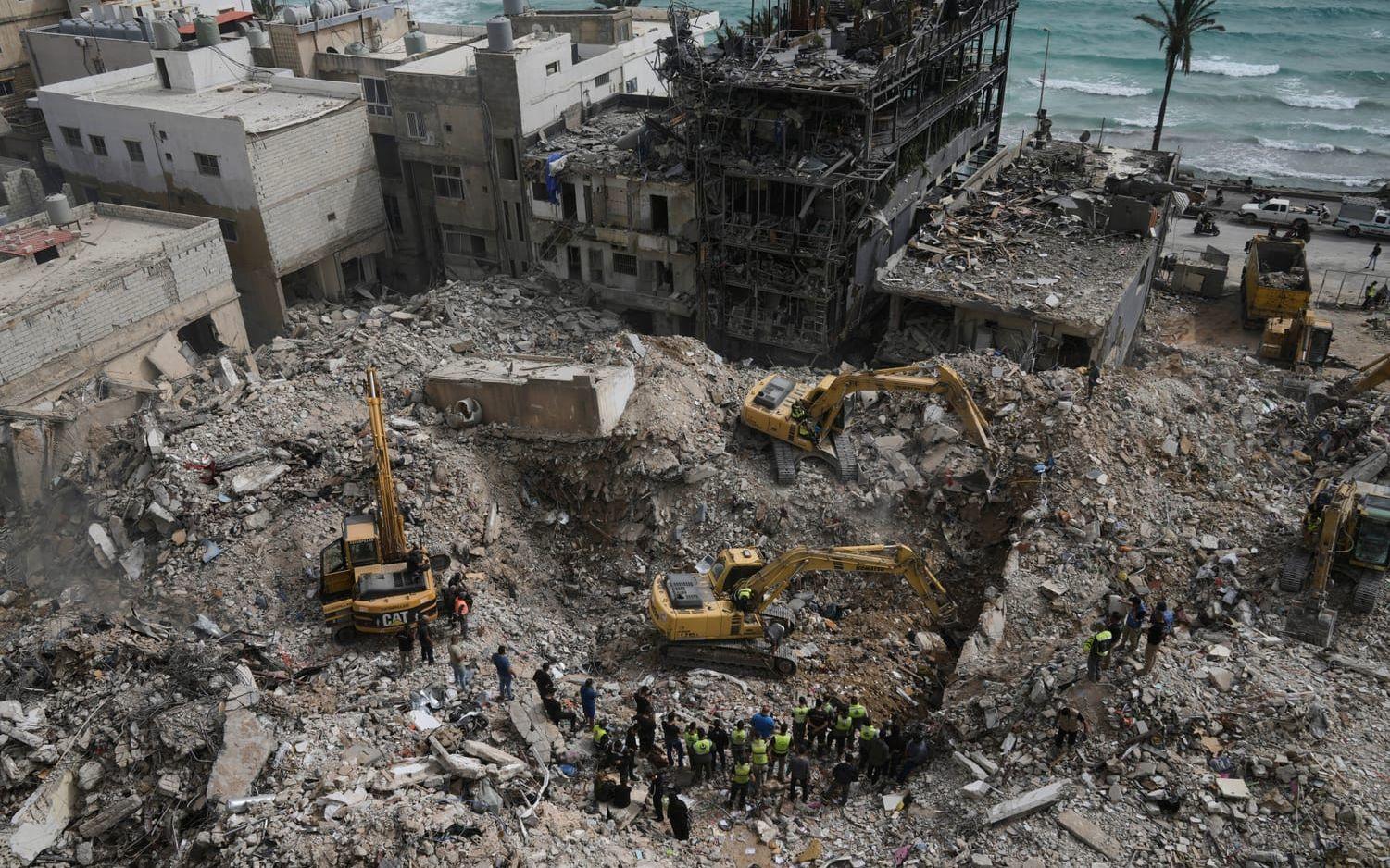 Grävmaskiner rensar bort spillror från byggnader som förstördes i israeliska luftanfall i staden Tyr på torsdagen.