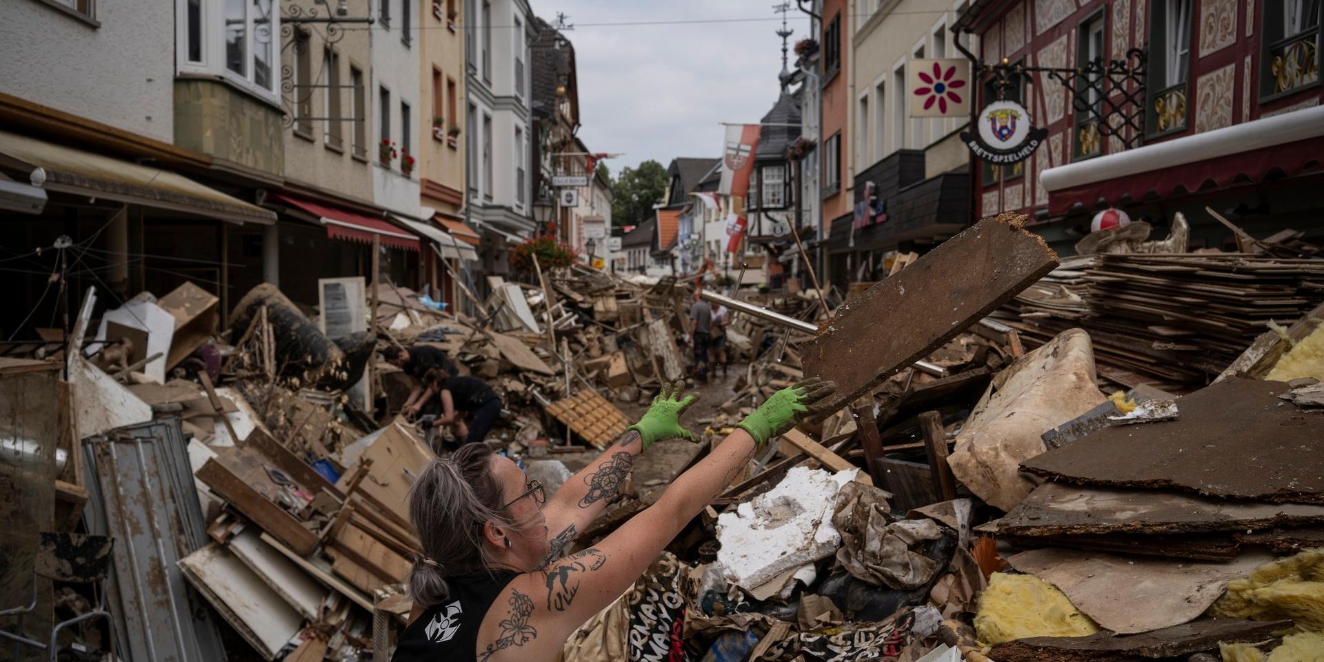 En kvinna slänger skräp i Bad Neuenahr-Ahrweiler i västra Tyskland, efter de översvämningar som skakat landet.