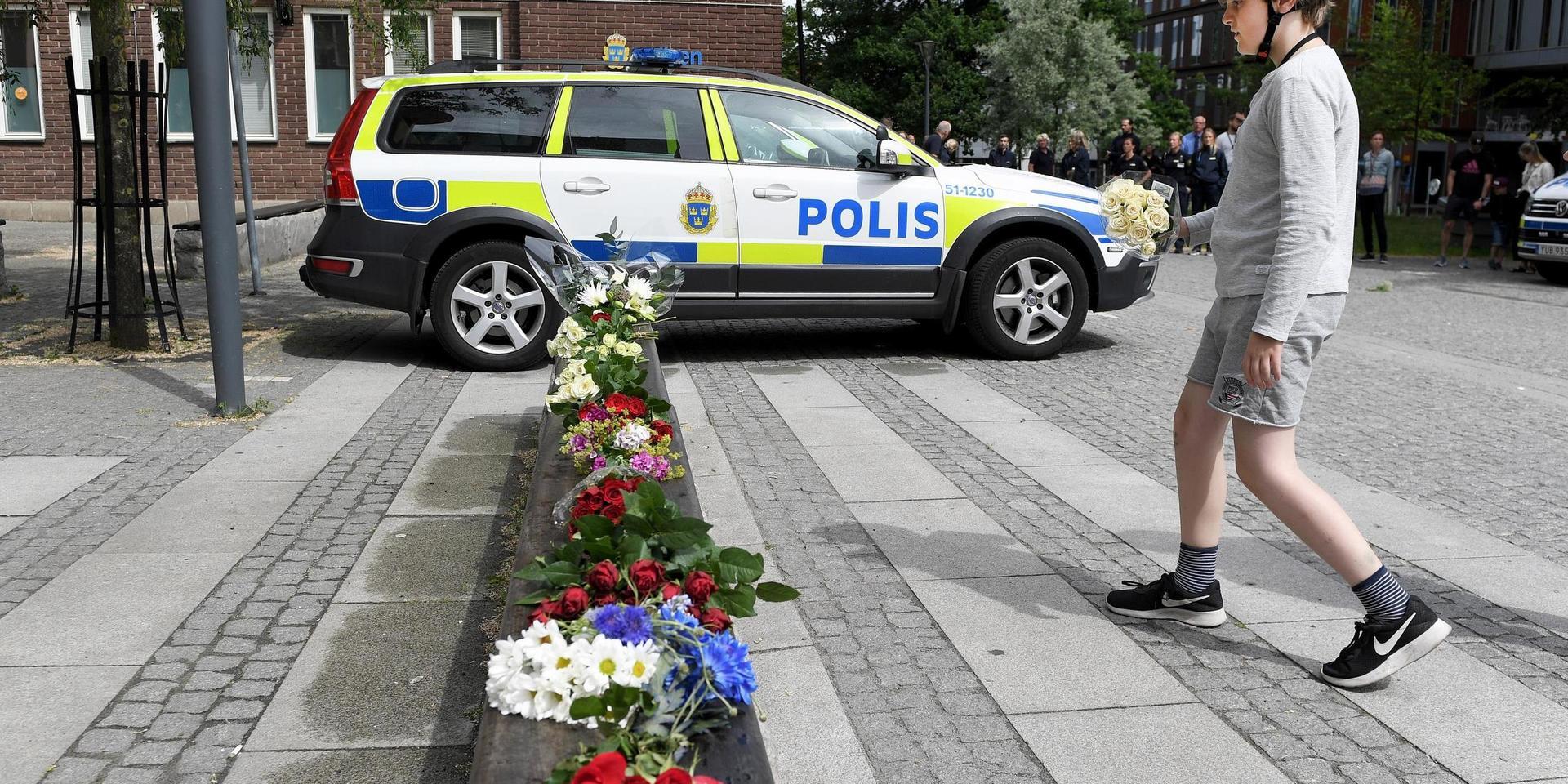 En pojke lägger blommor utanför polishuset i Göteborg för den polis som sköts till döds i Biskopsgården under natten. Runt om i landet höll poliser en tyst minut för sin förlorade kollega.