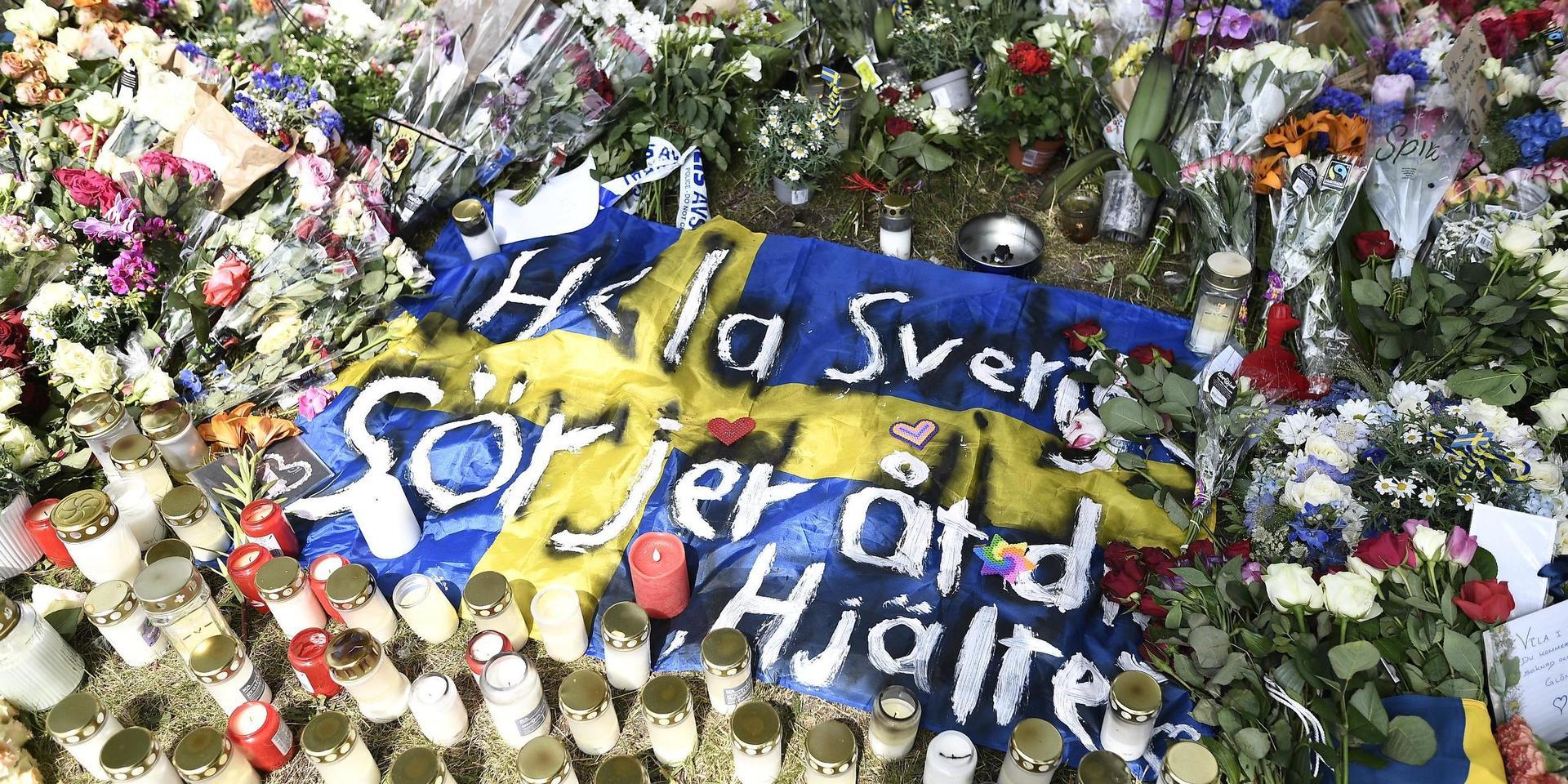 ”Hela Sverige sörjer” har man skrivit på en flagga, i mitten av minnesplatsen.