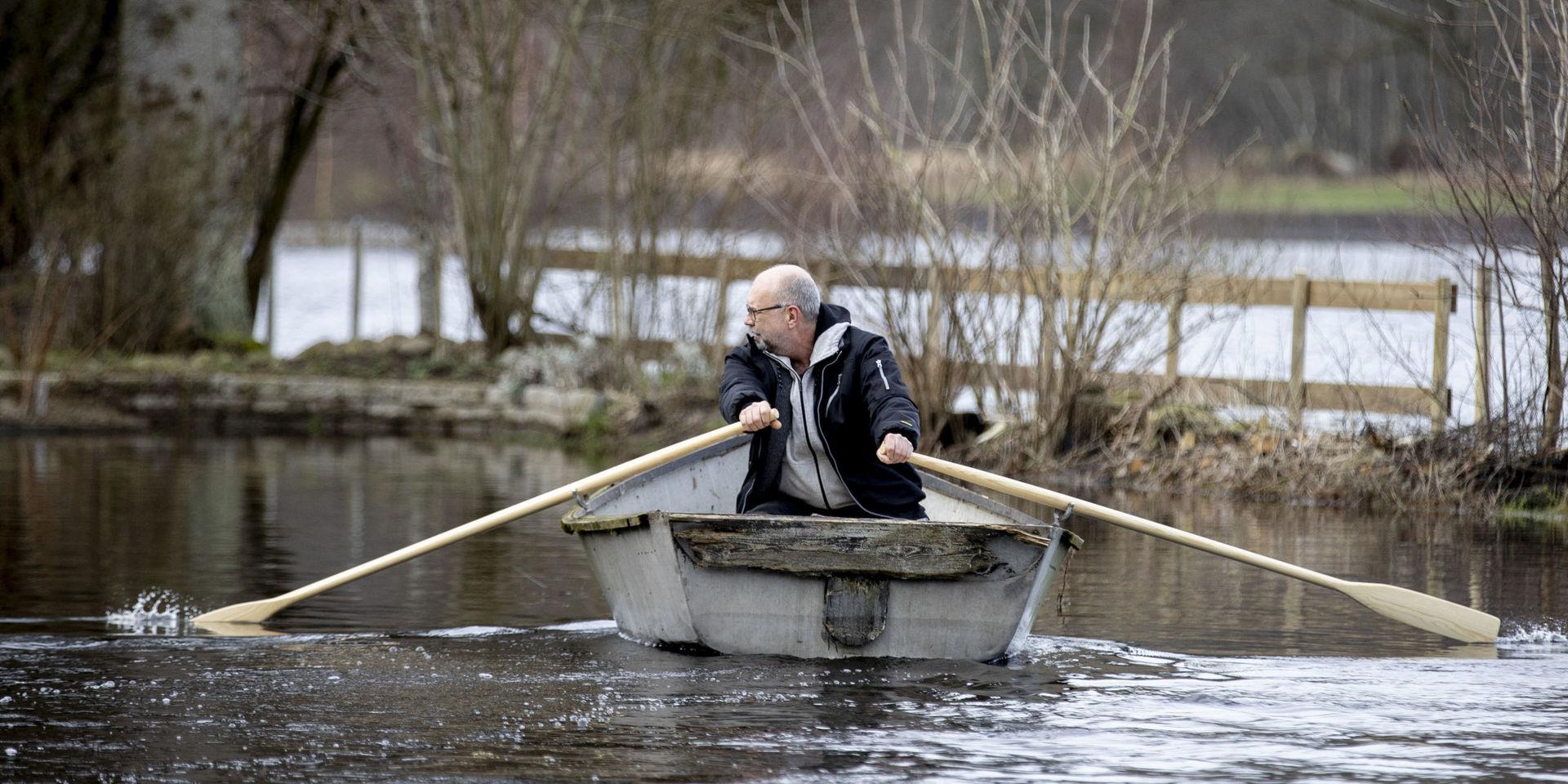 Mikael Jönsson får ta båten mellan hemmet och bilen då vägen är översvämmad vid Nissan i Åled. 