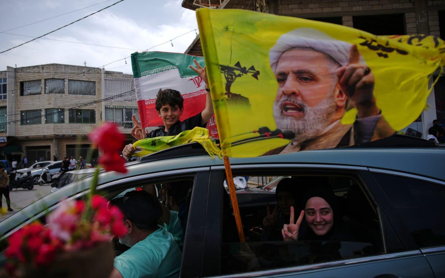 Libaneser som tvingats fly under kriget återvänder hemåt på fredagen, hållande en iransk flagga och en flagga med Hizbollahledaren Naim Qassem.