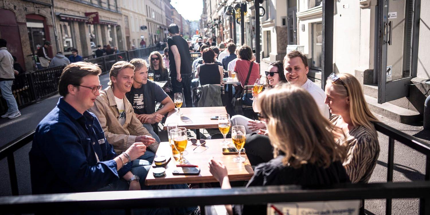 Glada människor som dricker öl på uteservering på Andra Långgatan. 