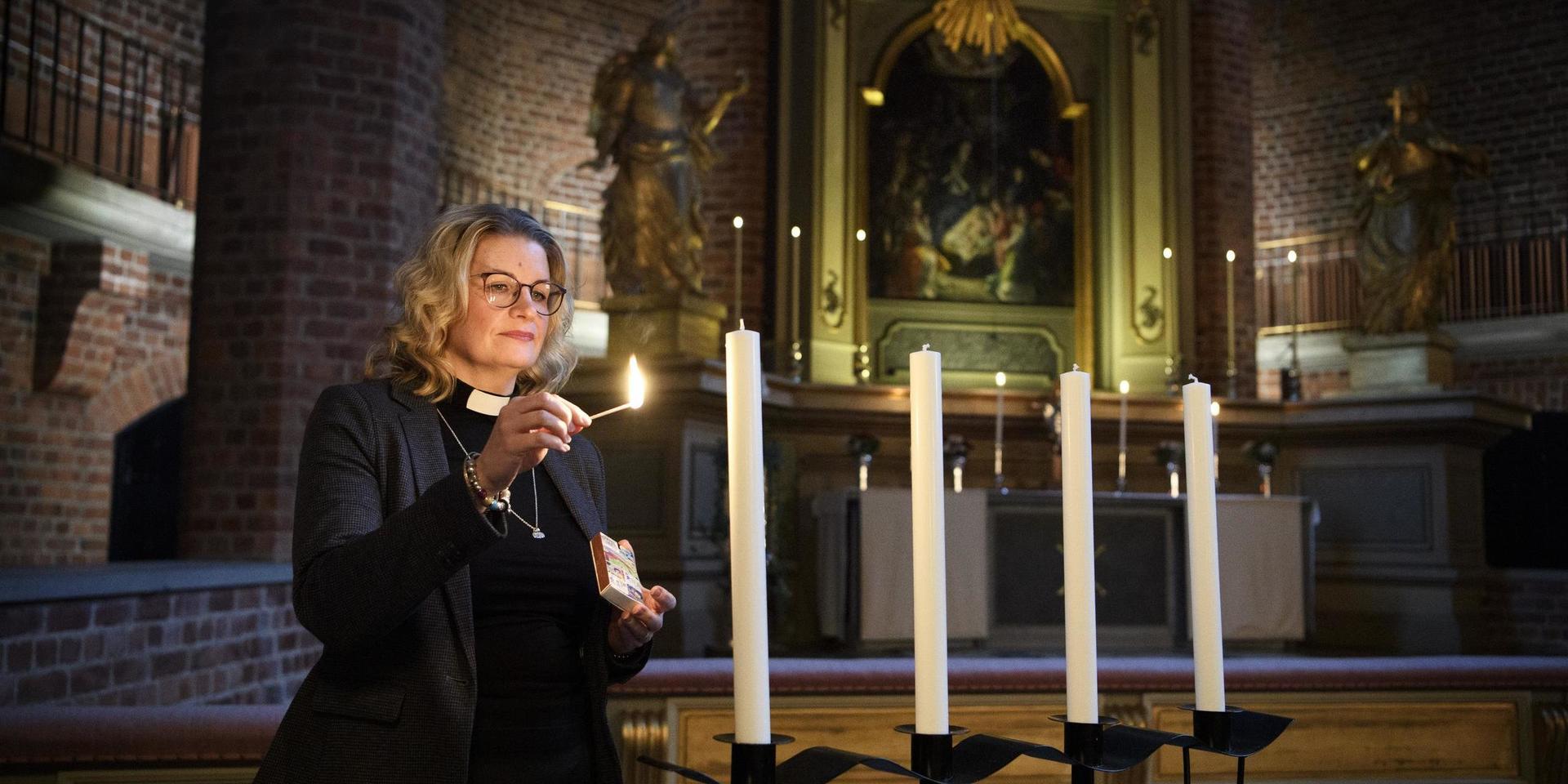 Gina Lindroos tänder ett ljus i adventsljusstaken i Klosters kyrka. I år blir det ingen körsång i advent, men kyrkan står öppen för ljuständning och samtal.