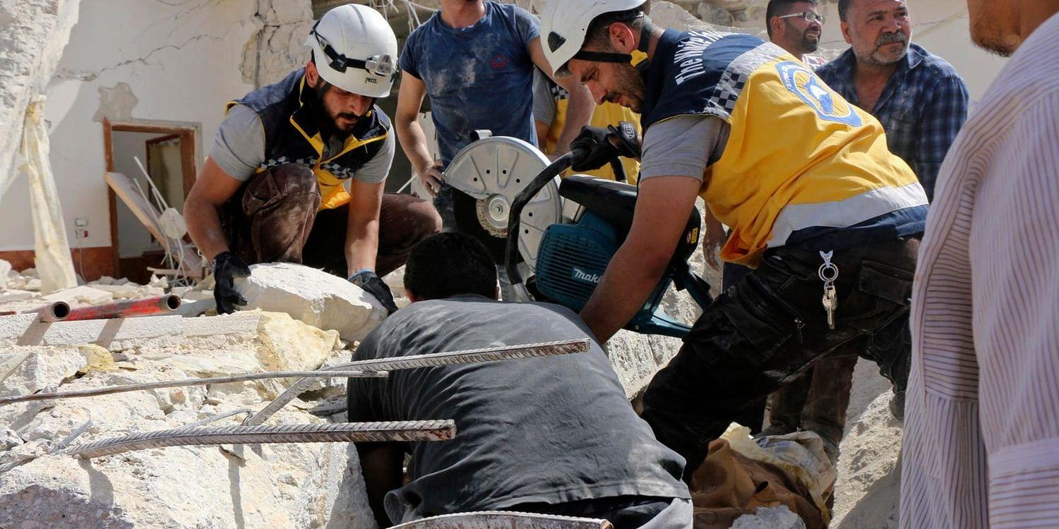 En bild som tagits av civilförsvaret Vita hjälmarna, och vars äkthet har verifierats av nyhetsbyrån AP, visar räddningsarbetare som på i torsdags letade efter människor i rasmassor efter ett flyganfall mot staden Maarit al-Numan i södra Idlibprovinsen.