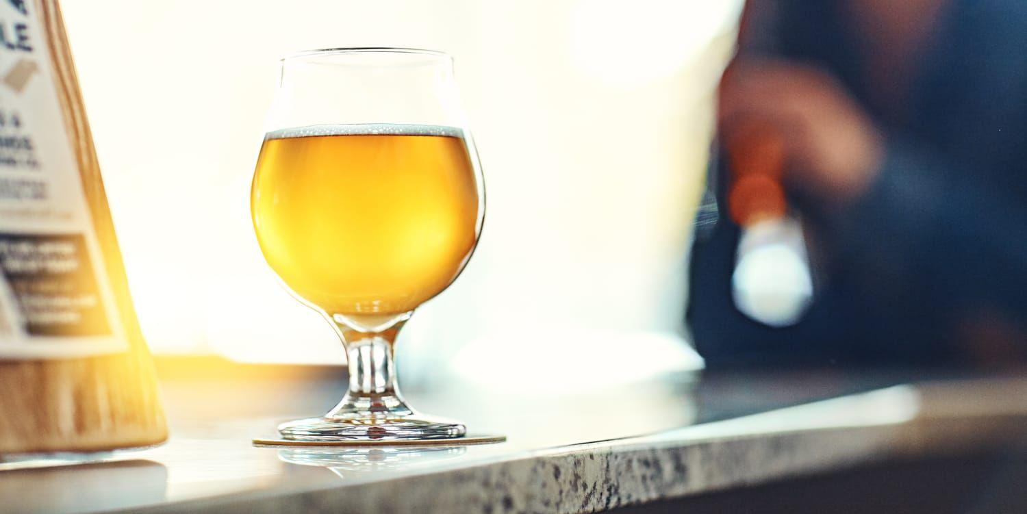 Ett upplyst glas med öl på ett bord.