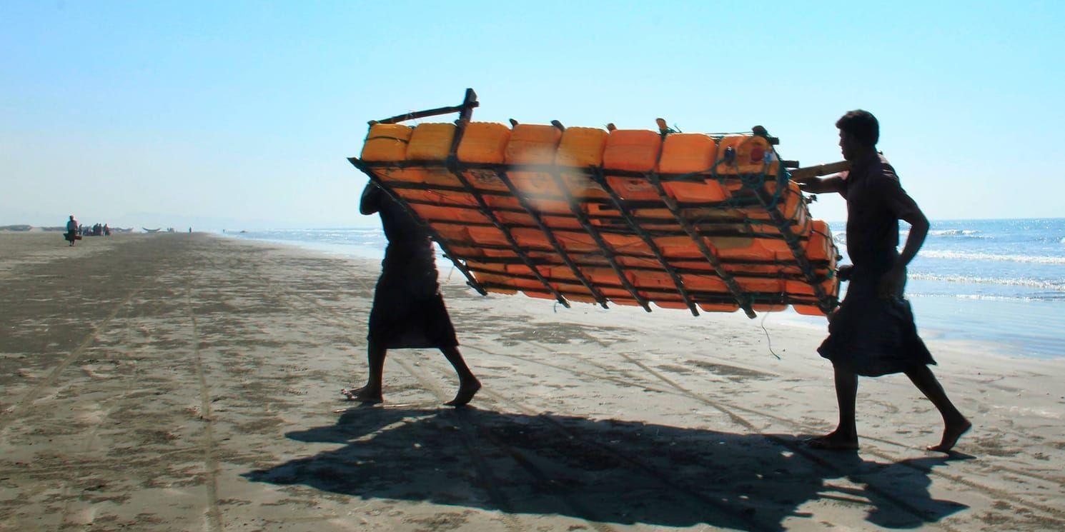 Fiskare tillhörande rohingya bär upp sin flotte gjord av platsdunkar. Arkivbild.