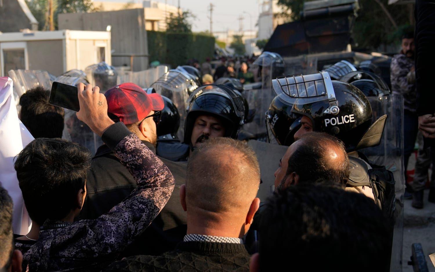 Säkerhetsvakter försöker lösa upp protesterna utanför den svenska ambassaden i Baghdad. 