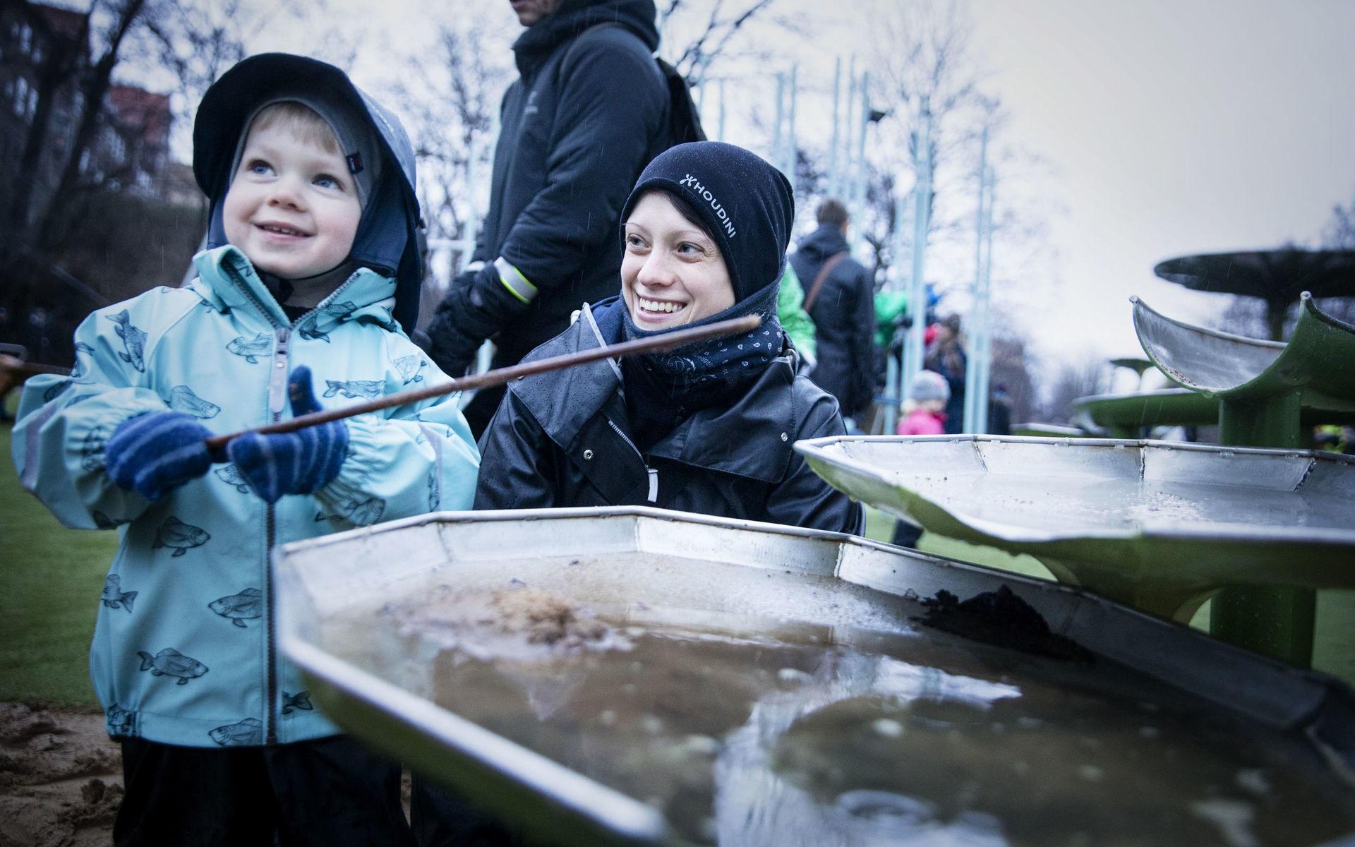 Sand och vatten. Alfred Andersson, 2år, blandar geggamoja. Mamma Johanna Andersson är med och inviger regnlekplatsen.