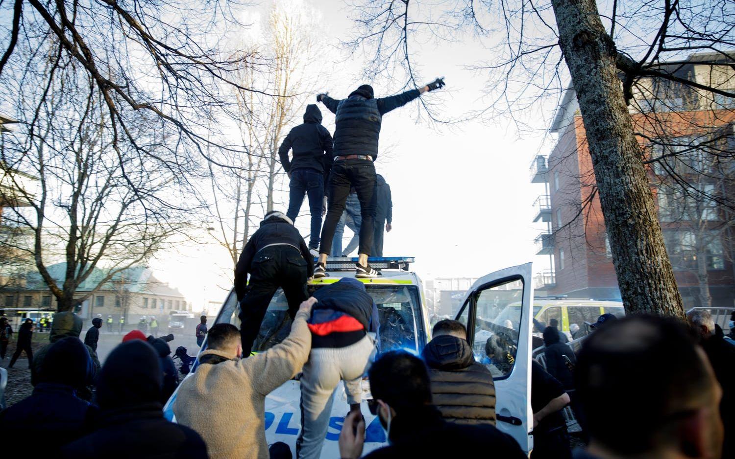 Motdemonstranter klättrar upp på en polisbuss vid Sveaparken i Örebro, där Rasmus Paludan, partiledare för det danska högerextrema partiet Stram kurs, har fått tillstånd för en sammankomst på långfredagen.